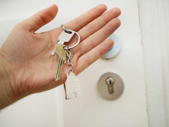 holding keys in front of house - email marketing for real estate