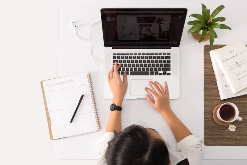 person working at desk with computer and notebook choosing platforms for online lead generation