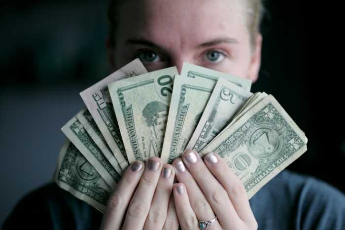 woman holding money in front of her face (setting a price for your product)