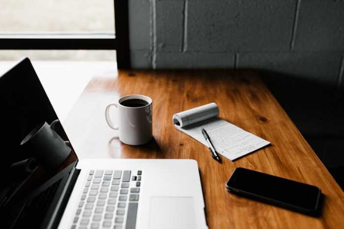 wooden desk with computer, coffee and notepad for blogging