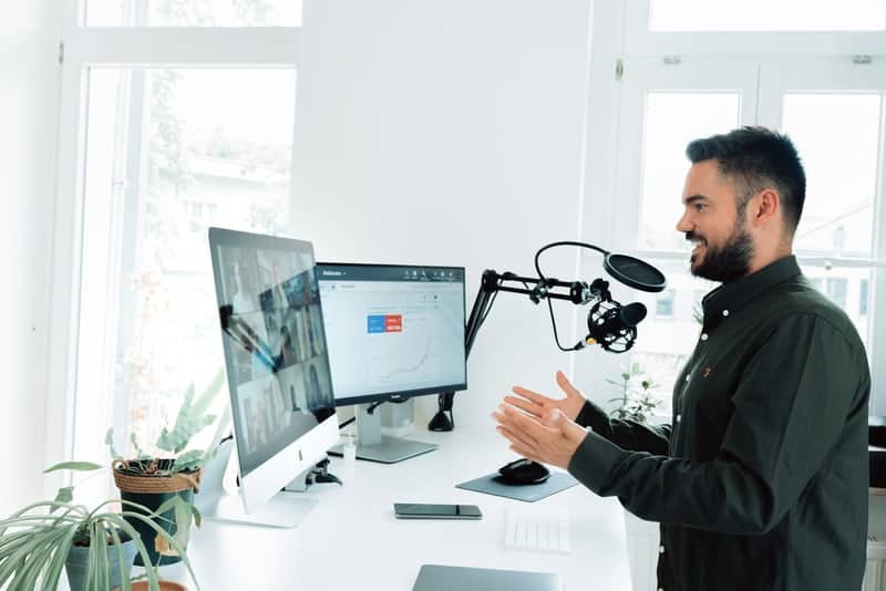 man in front of computer with professional microphone delivering webinar as an online lead generation tactic