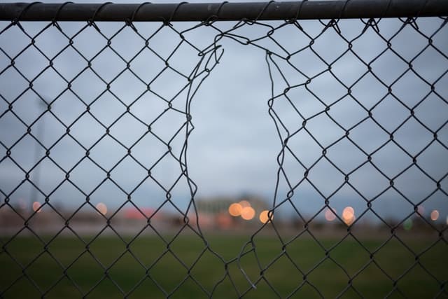 disruptive marketing represented by a chainlink fence with a hole in it