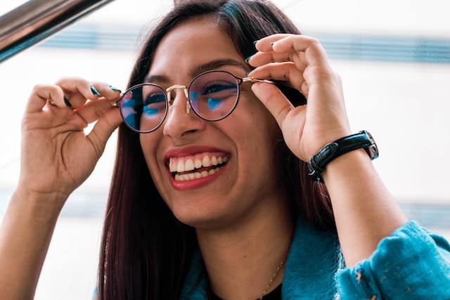 woman putting on glasses