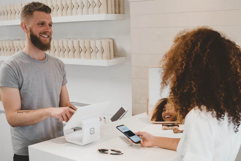 man in grey crew-neck t-shirt smiling to woman on counter - customer loyalty, customer retention, retaining customers