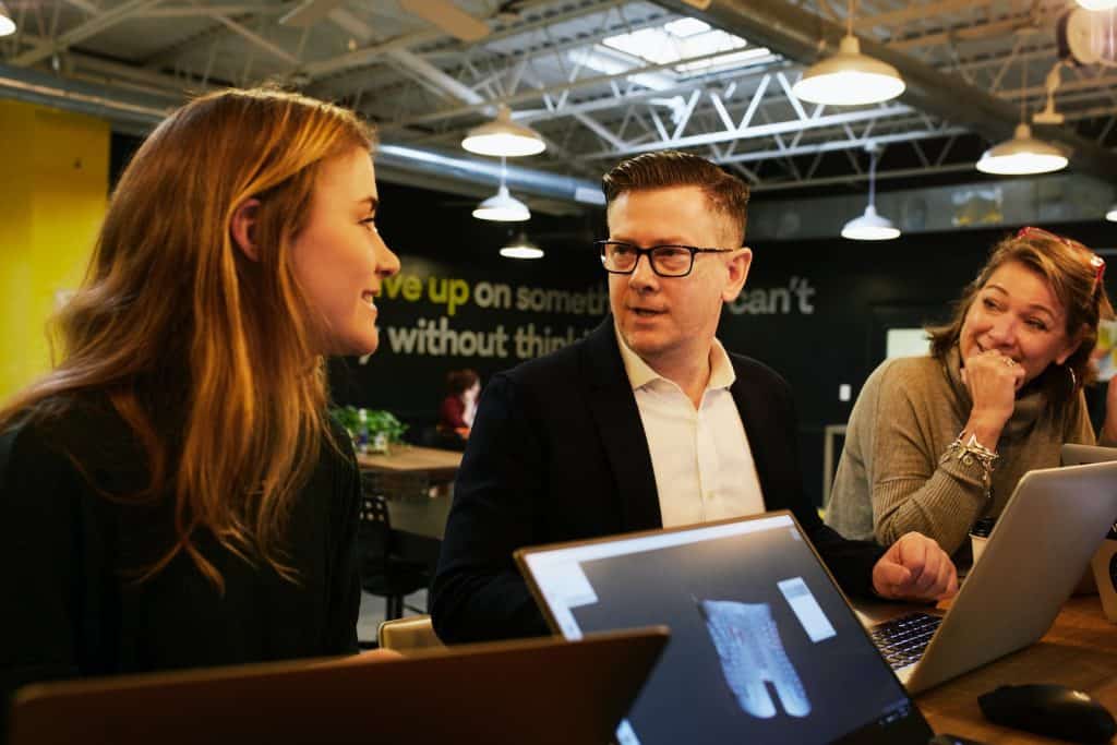 man and two women sitting beside table