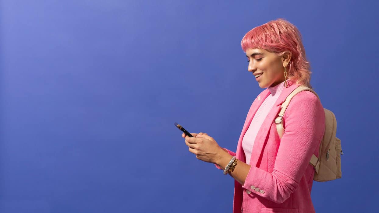 a woman with pink hair is looking at her cell phone