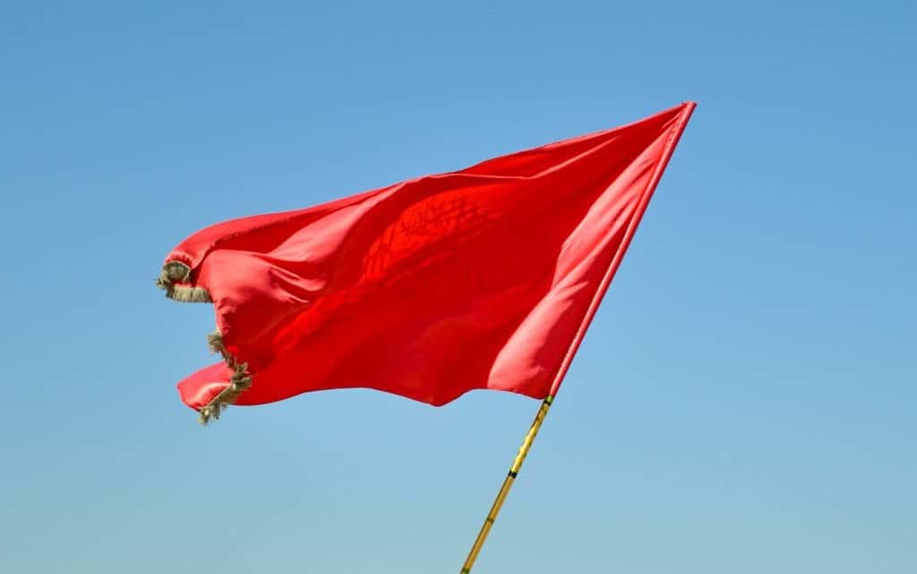 red flag on pole under blue sky during daytime