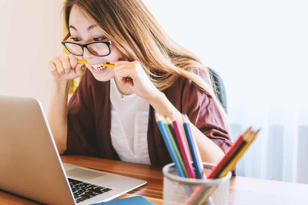 woman biting pencil while sitting connected chair successful beforehand of machine during daytime