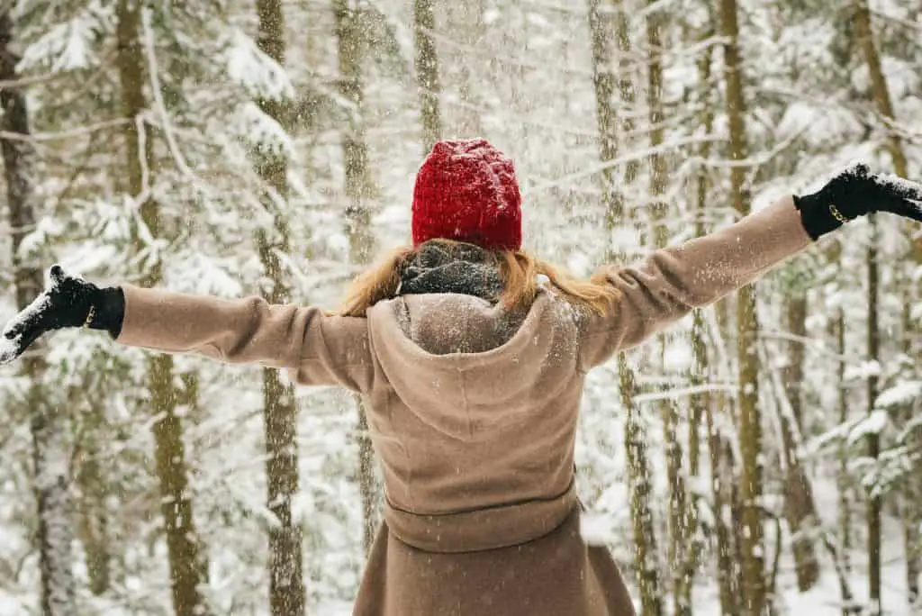 small business saturday woman wearing hoodie spreading her arm near trees with snows