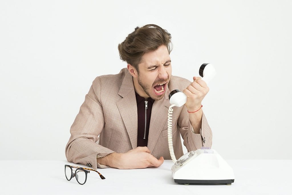 man holding telephone screaming - high-maintenance customer