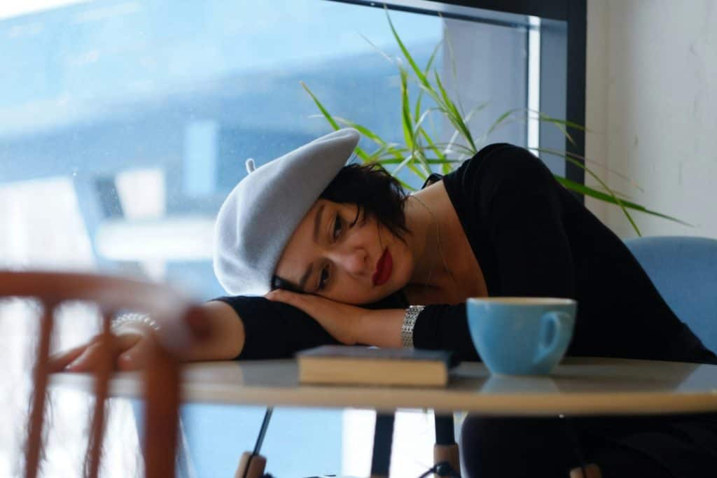 woman in black long sleeve shirt lying on white wooden table - procrastination tips for entrepreneurs