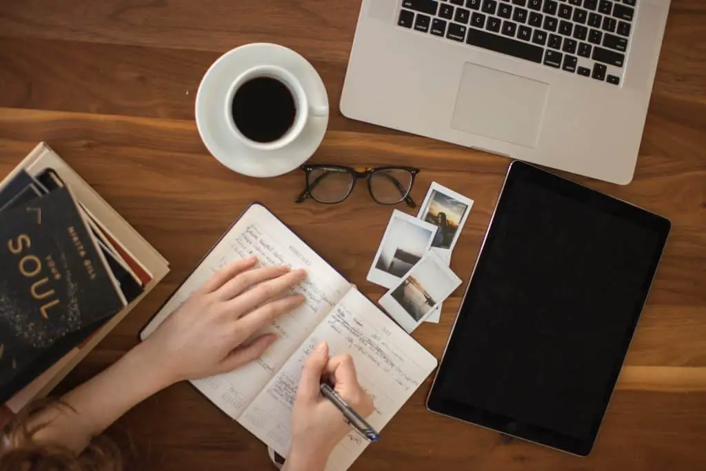 person holding ballpoint pen writing brand story formula on notebook