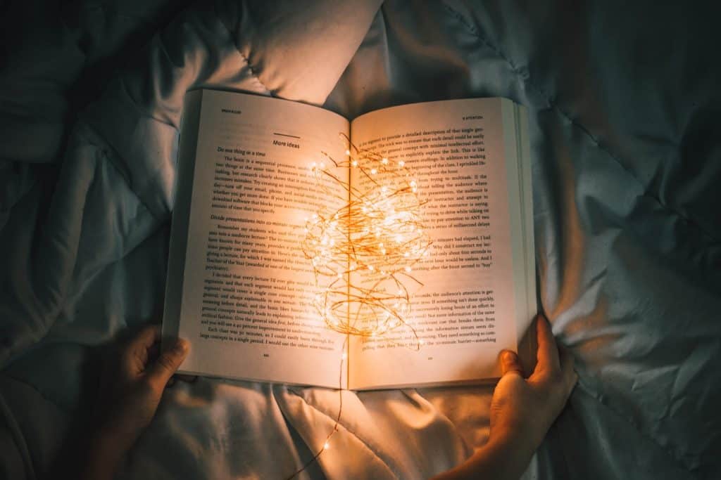 person holding string lights on opened book - storytelling techniques