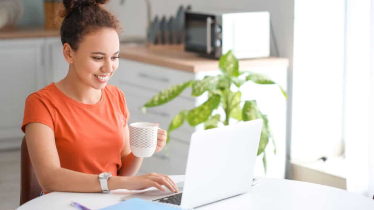 woman in red shirt at computer with plant