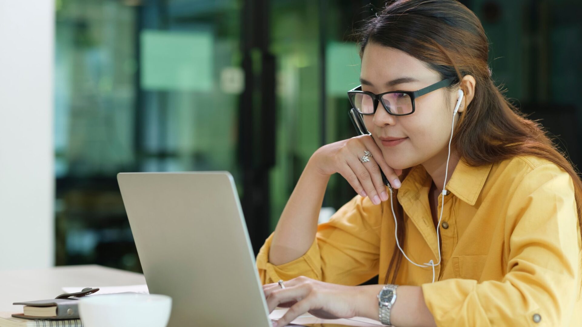 woman in yellow editing video at computer