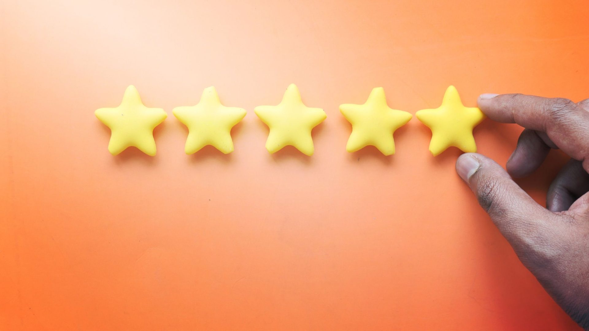 how to get more google reviews - orange background with a mans hand adding a fifth star