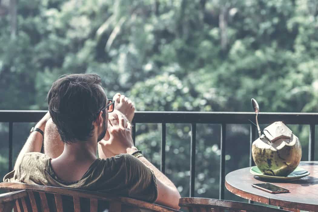 man sitting on armchair near table with opened coconut