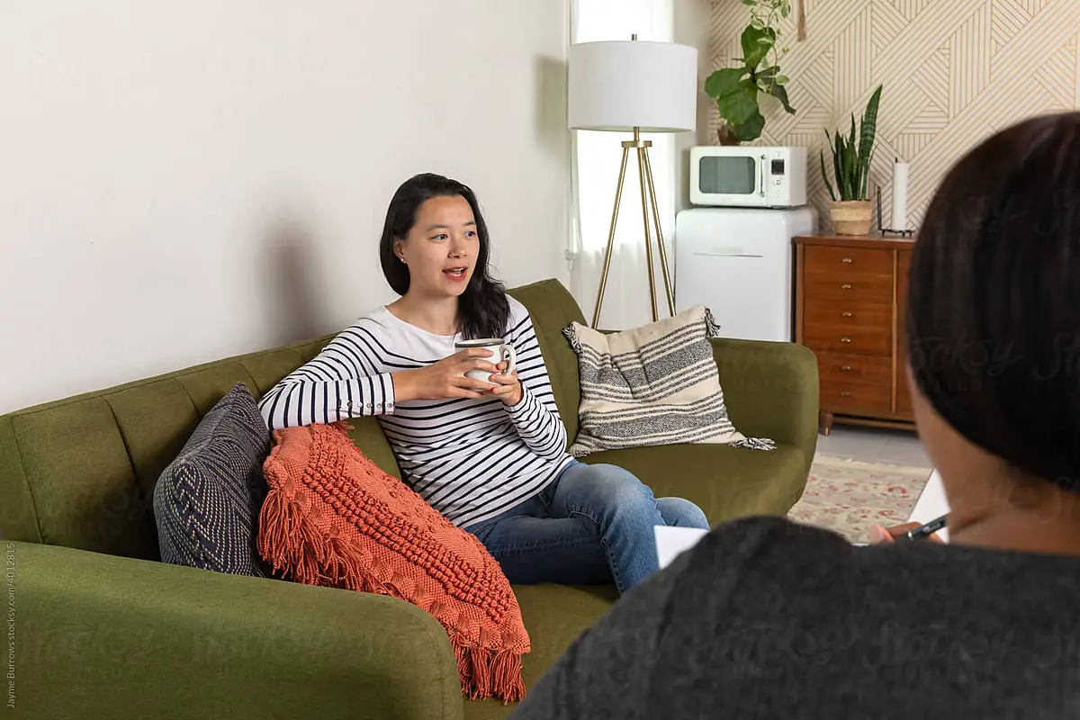 Woman sitting on couch in office talks to psychologist. Company analysis