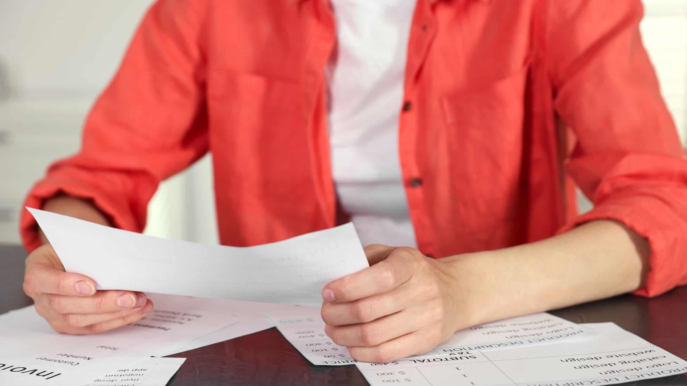 cutting customer service costs - man in red shirt going over documents