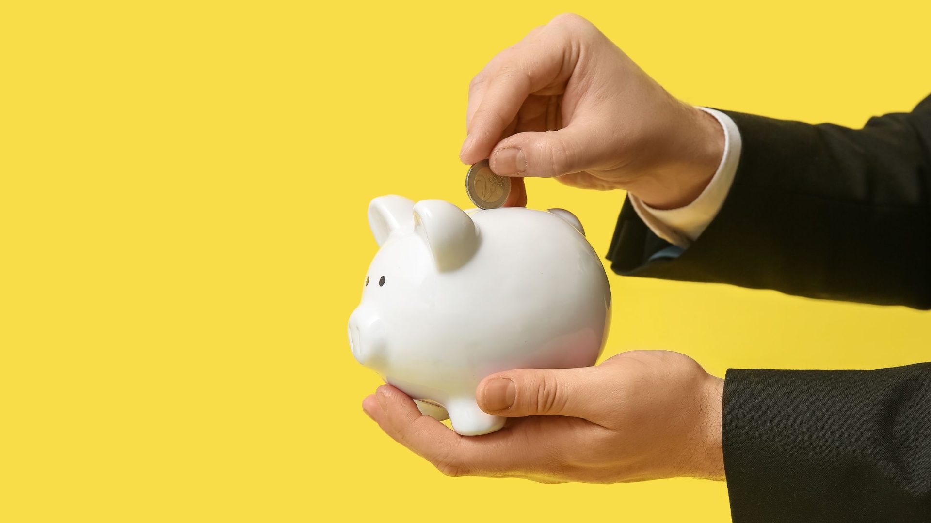 how to require a deposit from clients - man depositing money into piggy bank