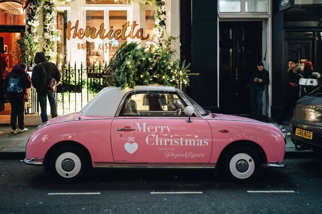 a pink car parked in front of a store - advertising with car wraps