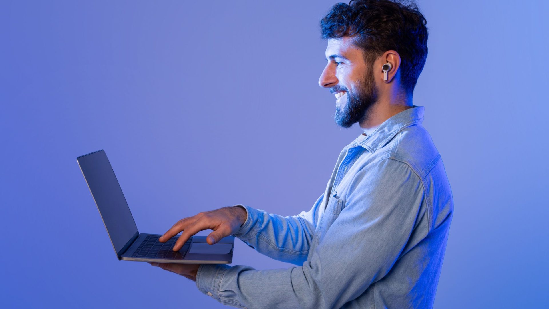 low cost marketing for small business Smiling man using laptop with earbuds.