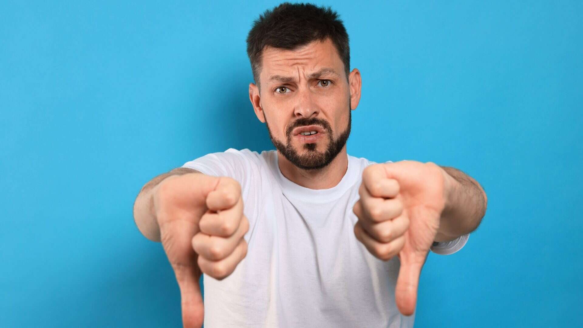 why marketing keeps failing. Man with beard with both thumbs down on blue background
