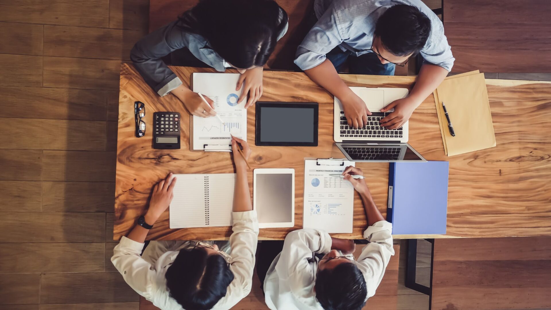 How to manage a marketing team - A diverse group of coworkers engage in a creative discussion around a business plan. They review color samples and notes, with a whiteboard displaying the plan and action steps in the background.