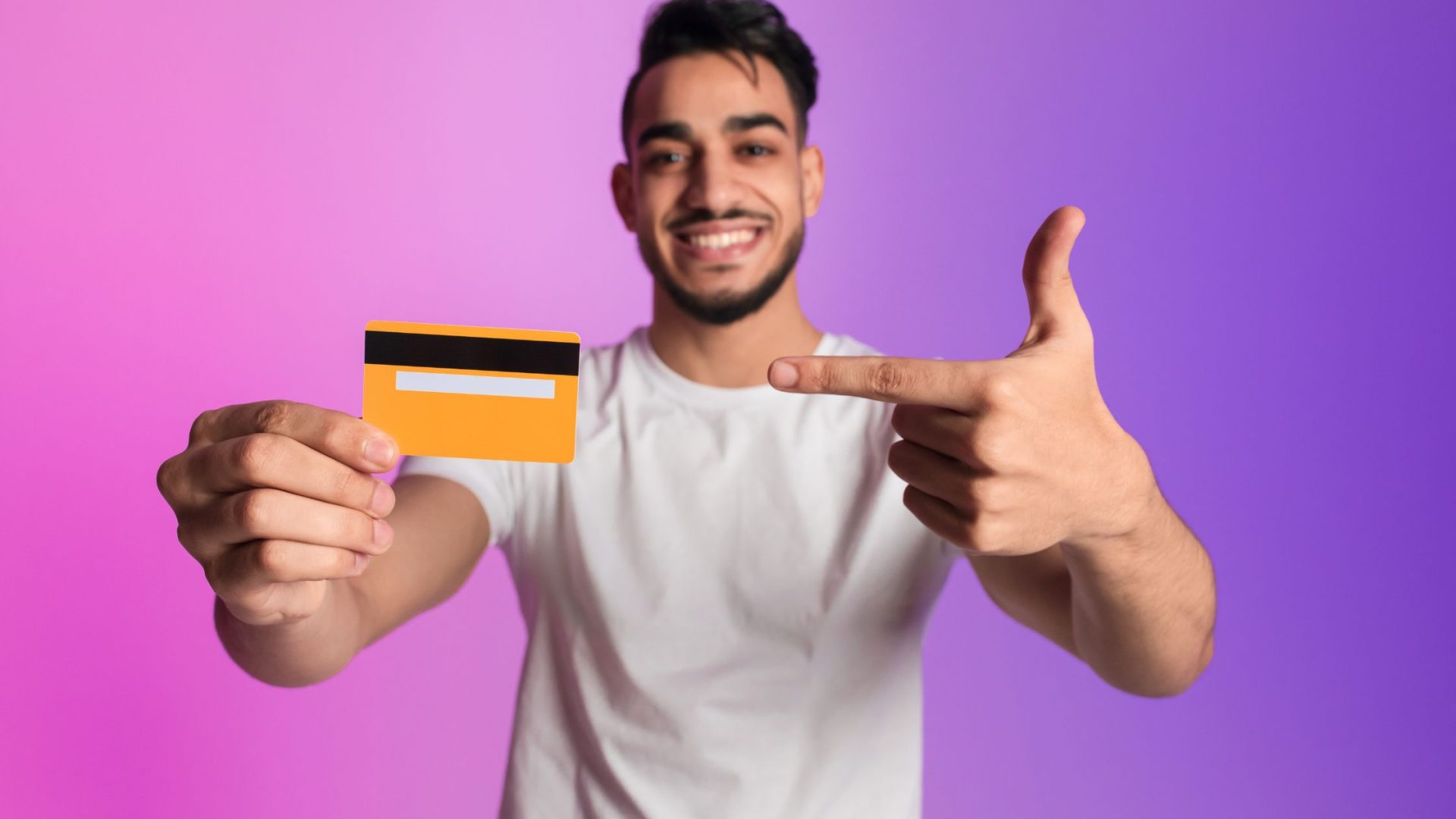 payment plans for small business. - young bearded man holding a credit card and pointing to it