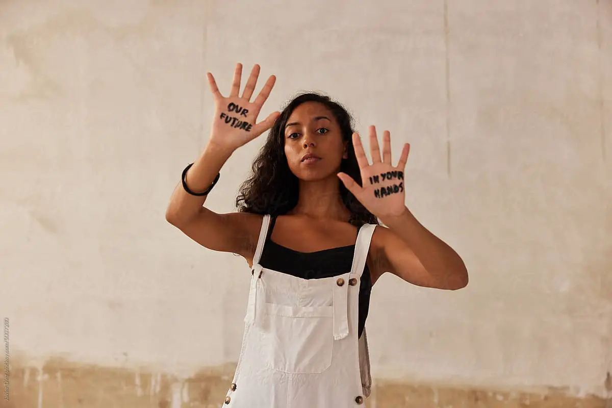 small business branding - Young woman showing Our Future In Your Hands inscription written on palms during protest campaign in daytime.