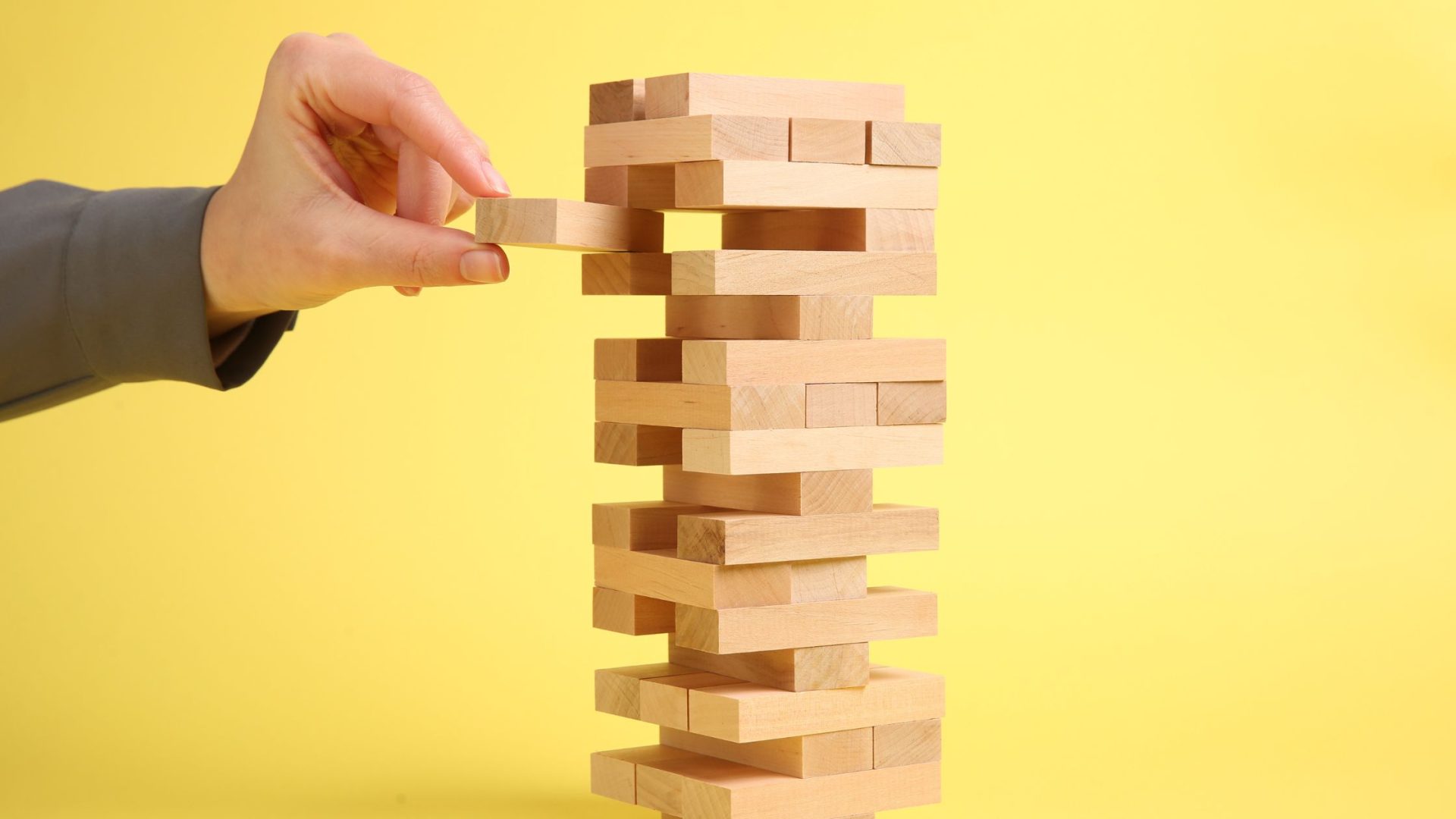 marketing strategies for small business. Man playing Jenga on yellow background