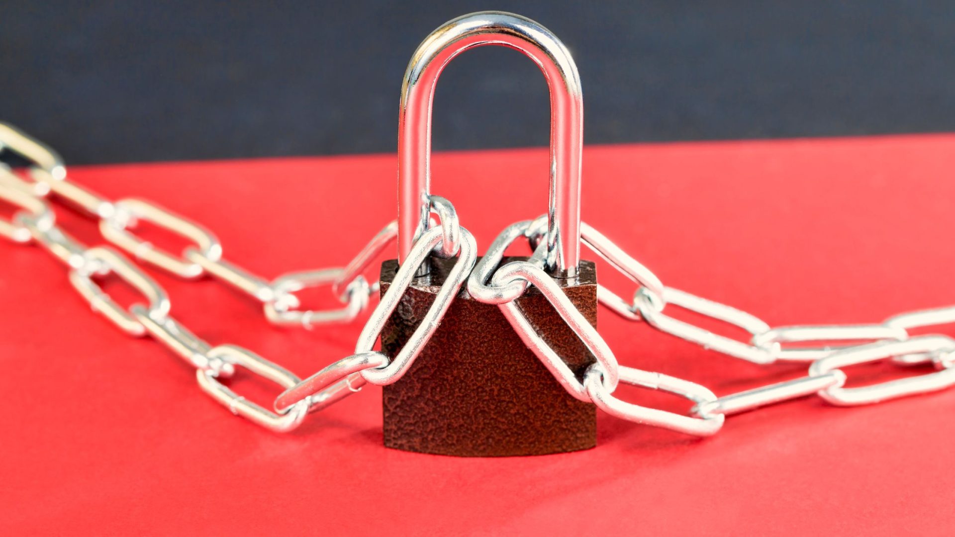 small business password security. Picture of a lock with chains on red background