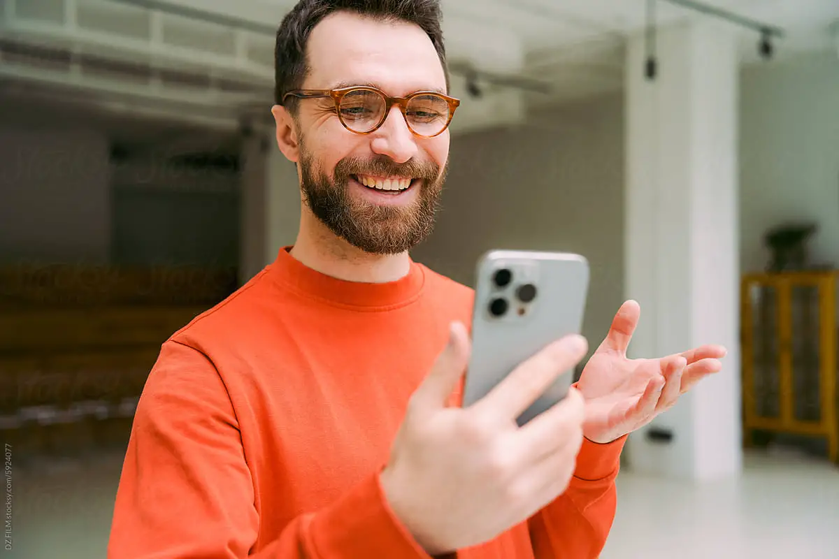 Man with beard in red shirt talking into iphone video tiktok vs youtube shorts video