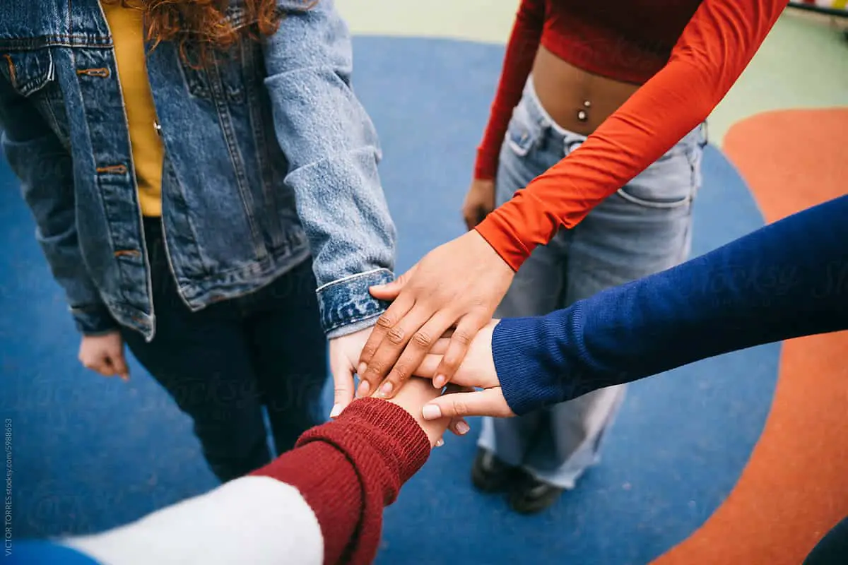 hire a virtual team - Hands of different colors come together in a gesture of unity and teamwork on a playground. The focus on hands emphasizes solidarity and diversity