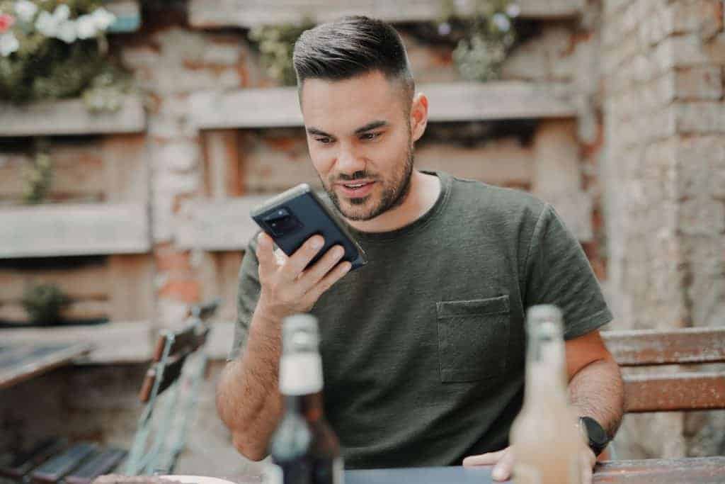 man in gray crew neck long sleeve shirt holding black smartphonevoice search google